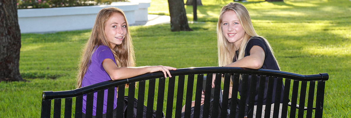 Two female students seated on a campus bench.