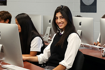 Smiling female student sitting at a computer.